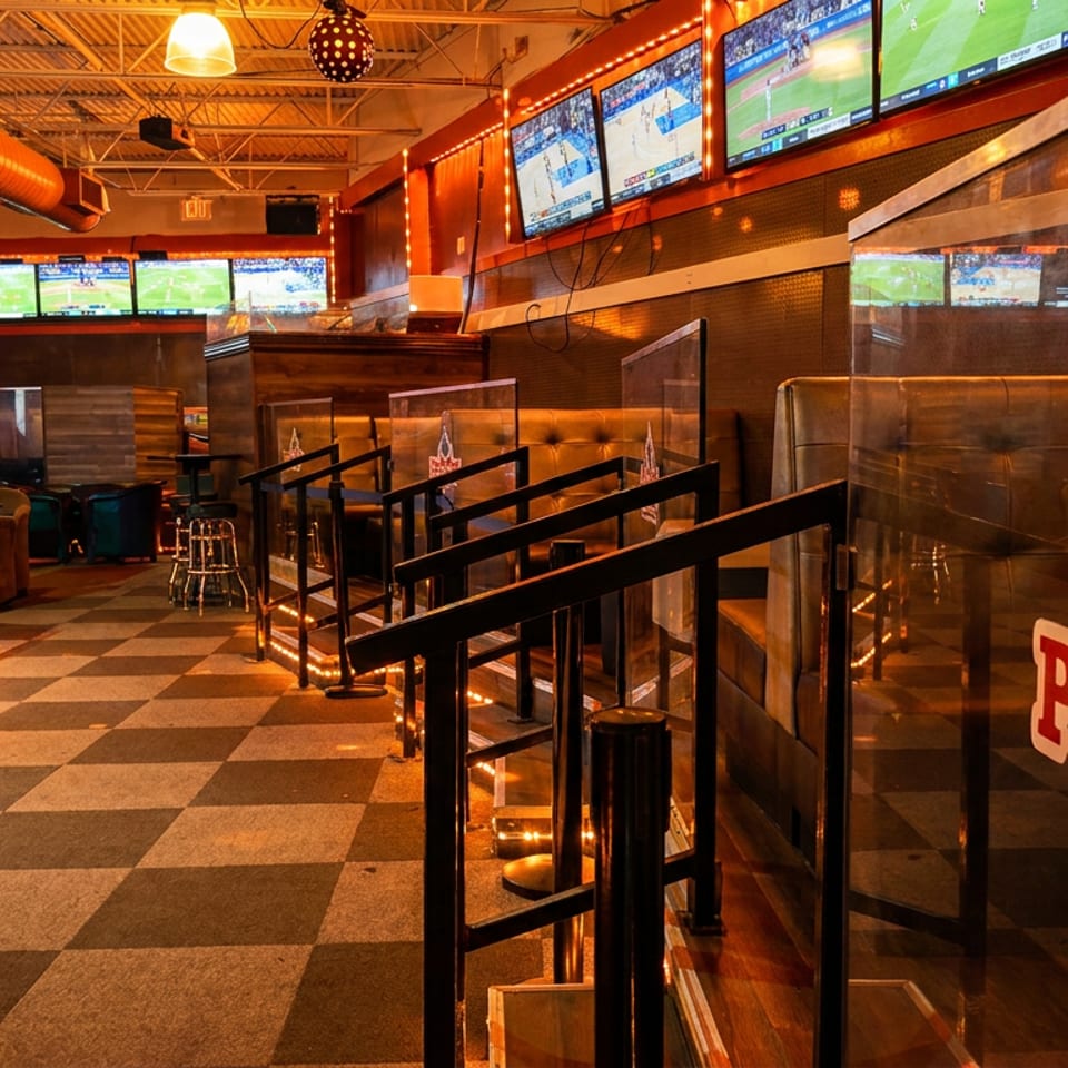 Interior of Prime 44 Sports Bar with multiple TVs showing sports, booths, and a checkered floor.